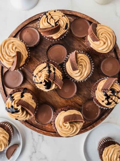 Chocolate peanut butter cupcakes on a wooden board.