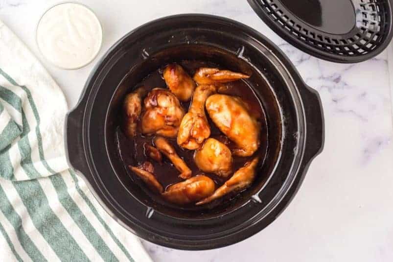 Chicken wings and bbq sauce in slow cooker.