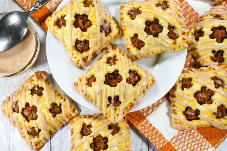 Three glasses filled with pumpkin smoothie and topped with whipped cream and sprinkled with cinnamon.