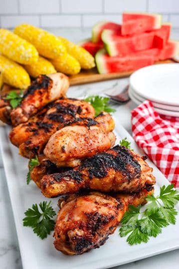 Grilled chicken drumsticks on a white platter.