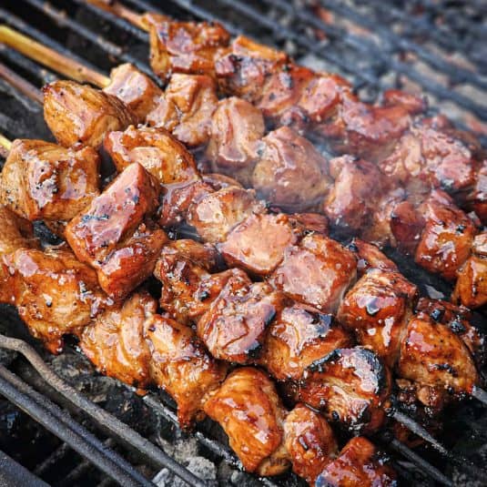 Grilled Filipino pork skewers cooking on a PK grill.