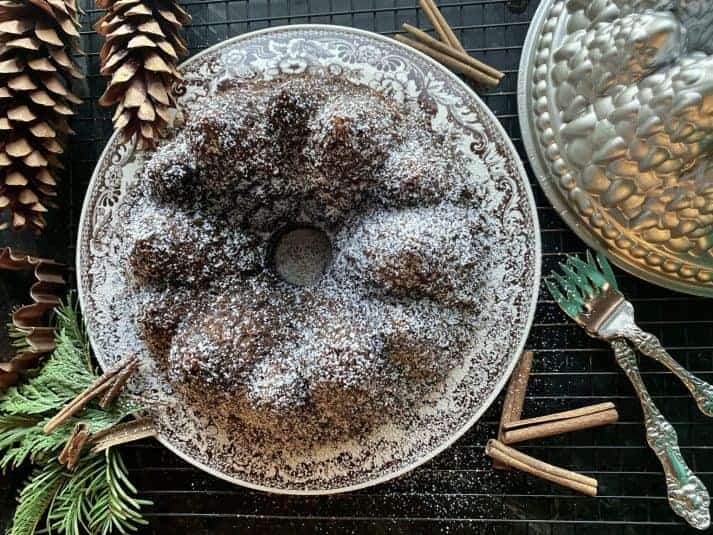 A bundt cake on a plate dusted with powdered sugar.
