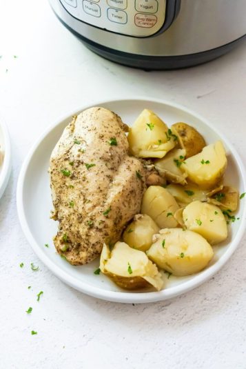 Instant Pot Chicken and potatoes with parsley on a white plate.
