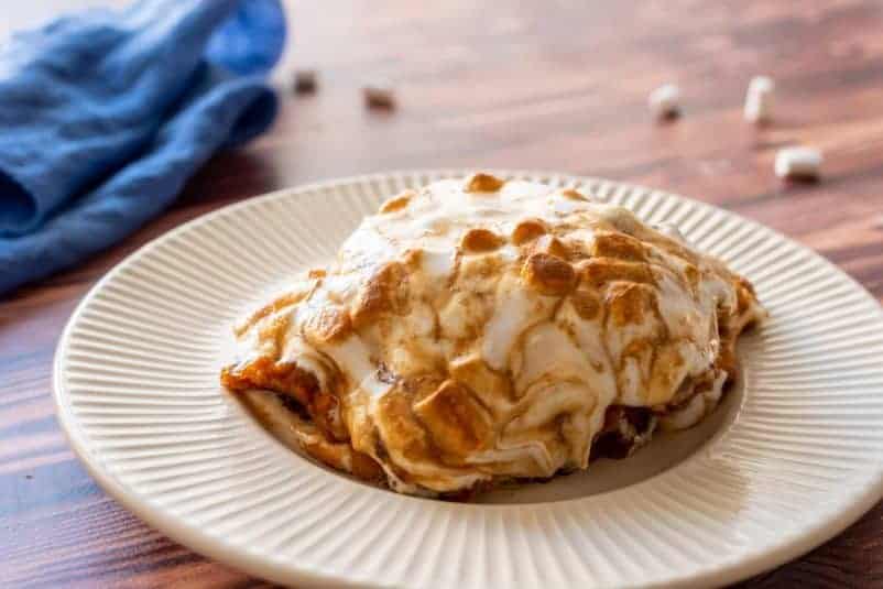 A serving of candied sweet potato casserole with marshmallows on a white plate.
