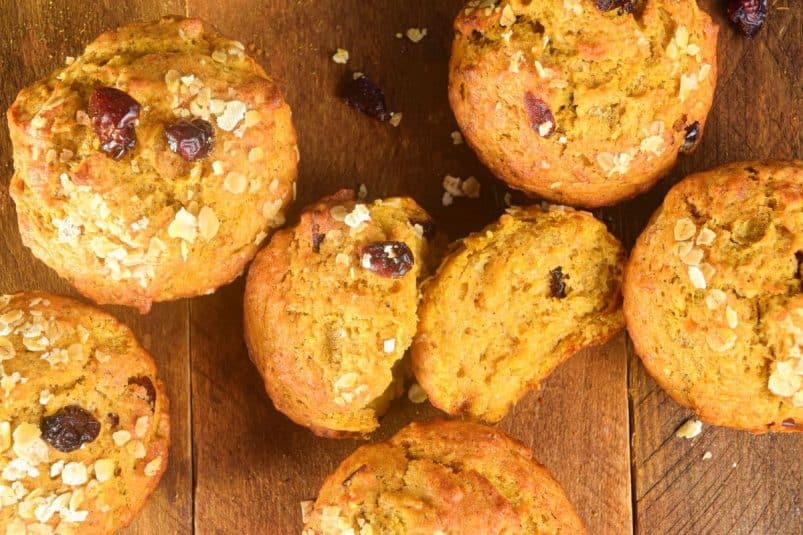 Pumpkin muffins with cranberries and oats on wooden background.