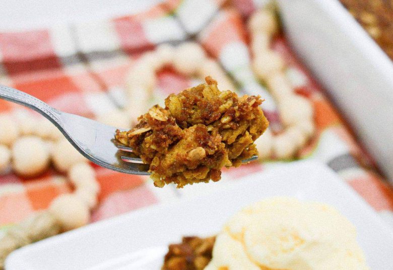 A white bowl filled with almond bark with candy and cereal.