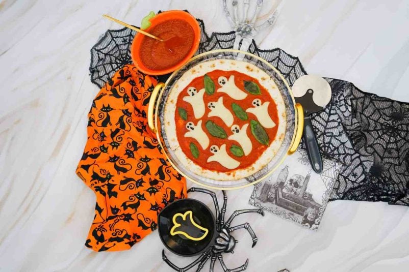 Overhead shot of a pizza for Halloween with ghosts out of cheese.