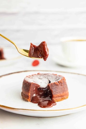 Picking up a piece of red velvet lava cake with a golden spoon.