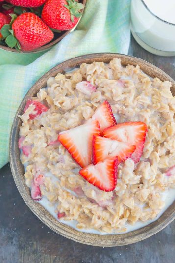 A bowl of strawberries and cream oatmeal, garnished with fresh strawberry slices.
