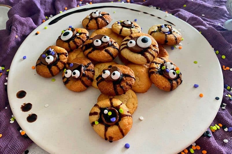 Sugar cookies decorated with chocolate syrup , sprinkles and scary eyes.