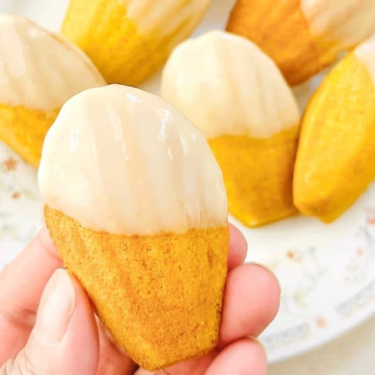 A hand holding a glazed sweet potato madeleines.
