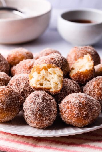 tofu donuts on a white plate coated in cinnamon sugar.