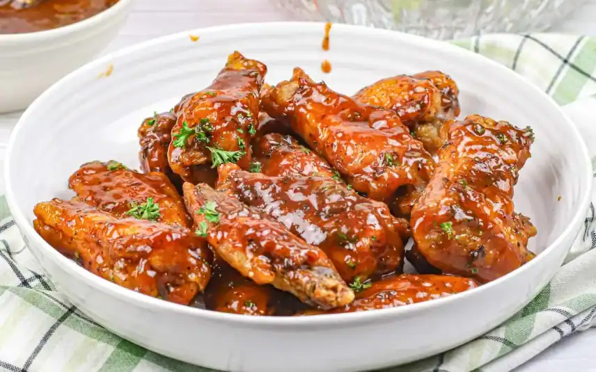 Sweet, glazed monkey bread pieces served in a white bowl, drizzled with icing.