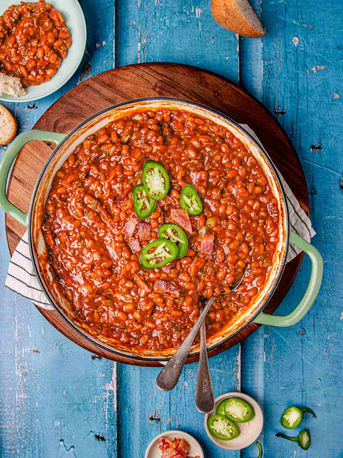 Bean and beef in a cast iron pan with bread on a flat surface.