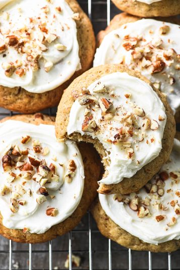 Banana bread cookies with cream cheese frosting on a cooling rack.