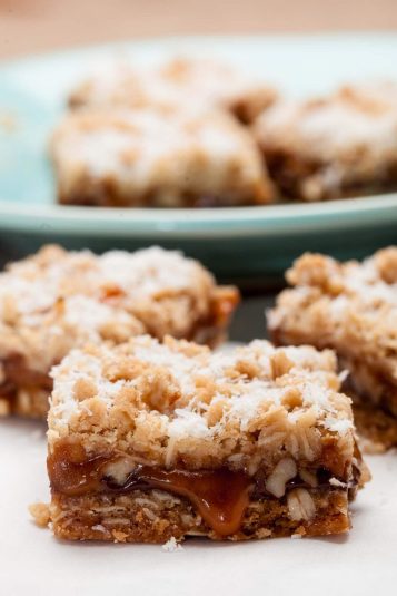 Closeup shot of caramelita bars with caramel oozing out and topped with finely shredded coconut.