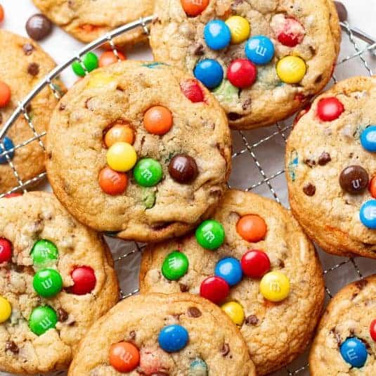 A stack of chocolate chip M&M cookies showcasing a mix of gooey chocolate chips and colorful M&M candies in a thick, golden cookie dough. These cookies capture the perfect balance of chocolate and candy, making them ideal for anyone craving a fun twist on traditional chocolate chip cookies.