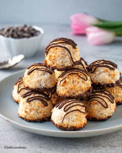 Chocolate dipped coconut macaroons piled on a blue plate.