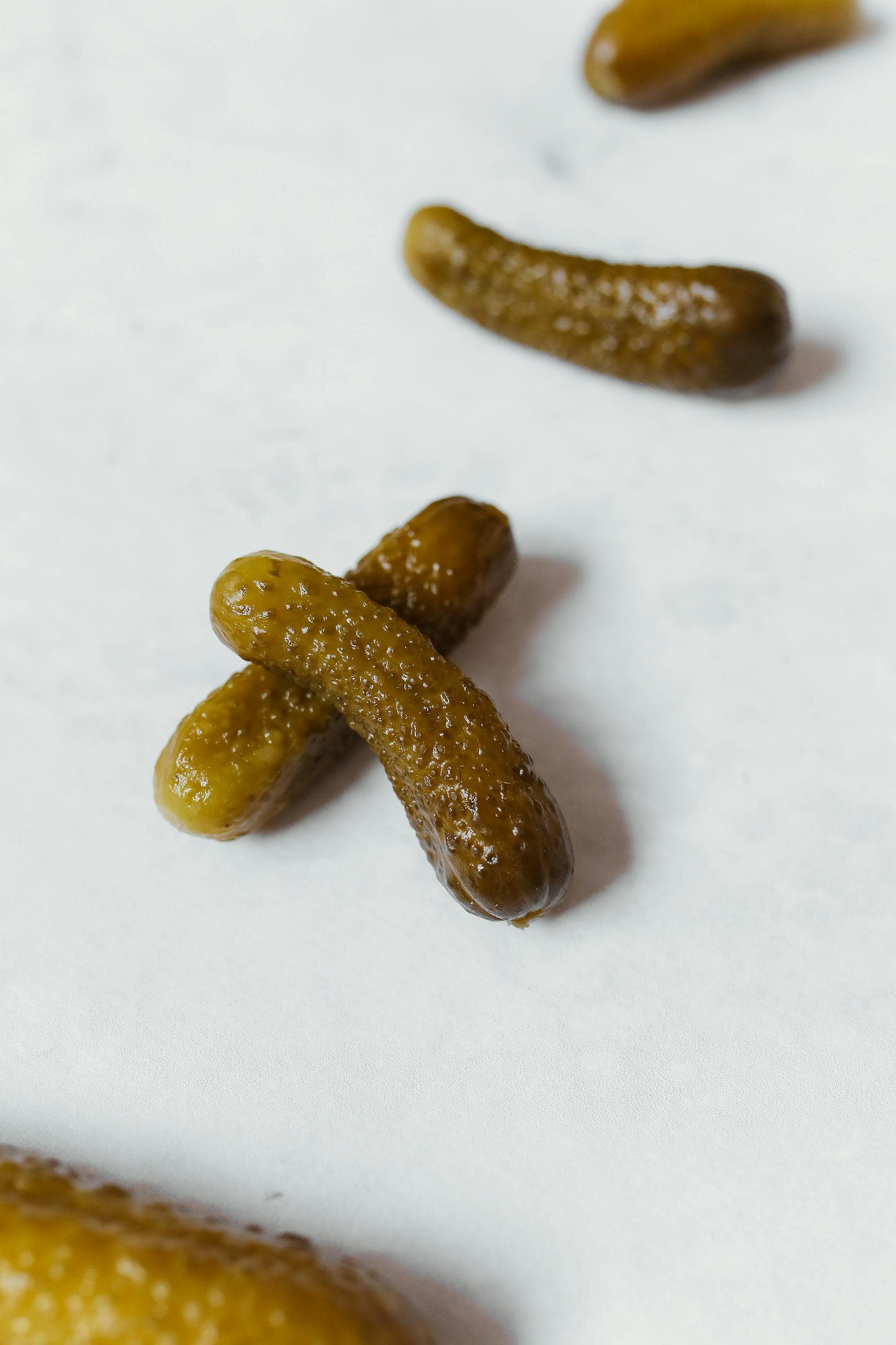 Detailed shot of pickled gherkins on a white background, showcasing their texture.