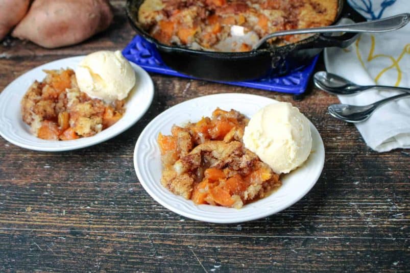 Easy Sweet Potato cobbler in 2 round white bowls and a scoop of vanilla ice cream in both .