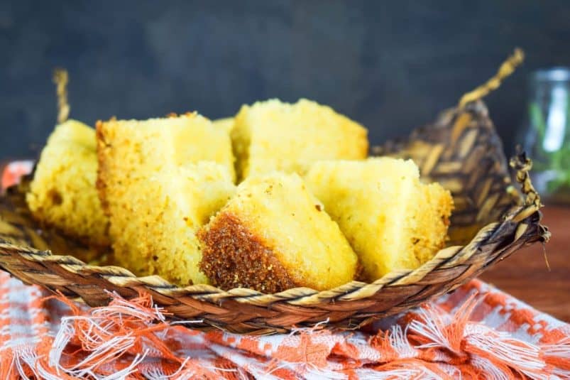 Electric skillet cornbread pieces in woven dish on kitchen towel.