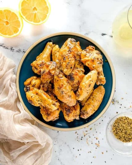 A white bowl of Instant Pot Chicken Stew sits on a rustic wooden cutting board with a red linen on a white marble counter.