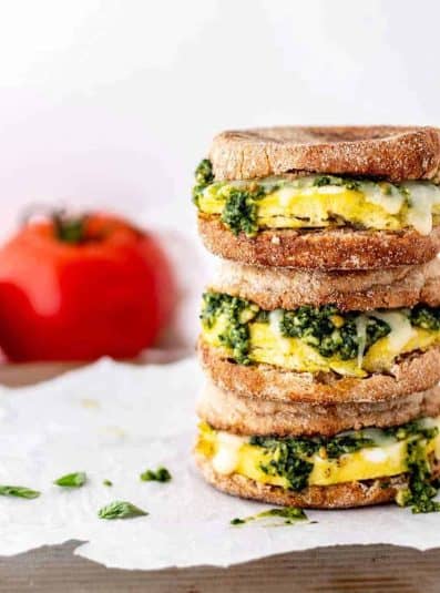 Close up image of three pesto egg breakfast sandwiches stacked on top of each other.