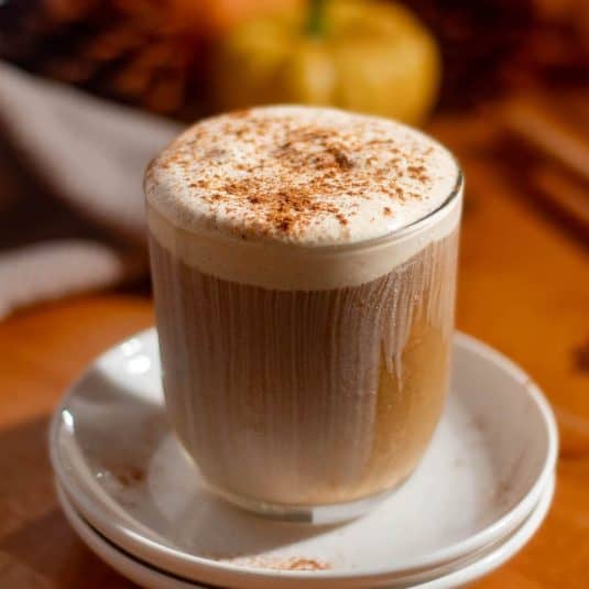 Homemade pumpkin cold foam recipe served over iced coffee with a creamy cinnamon-spiced topping.