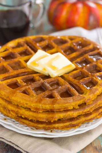 Stack of Pumpkin Spice Waffles drizzled with butter and syrup.
