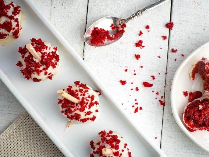 Red velvet cake pops in white dish on white wooden background.