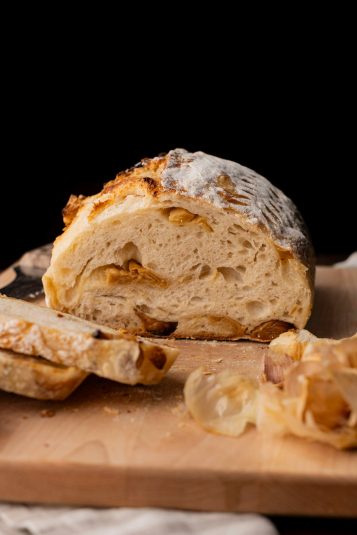 Roasted garlic sourdough with 2 slices on wood board.