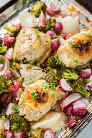 Sheet Pan Chicken and Vegetables on a sheet pan with foil, broccoli, onions, radishes, and parsley.