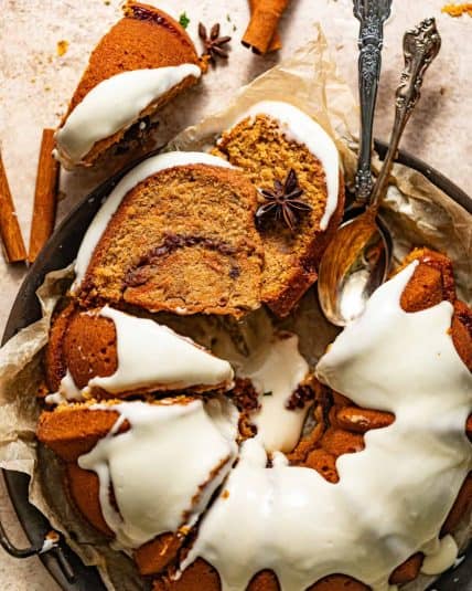 Sweet potato pound cake topped with. cream cheese frosting on a serving plate with spoons.