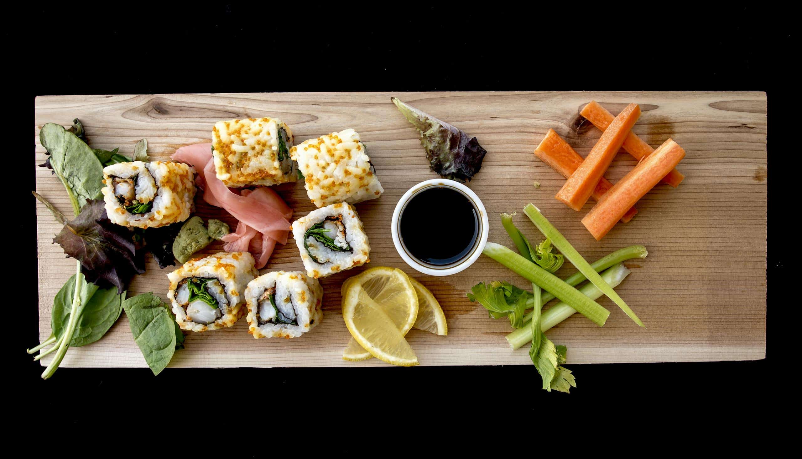 Top-down view of a sushi platter with fresh vegetables, perfect for a healthy meal.