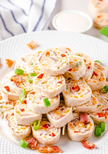 Stacked Cheddar Bacon Ranch cream cheese Pinwheels on white plate.