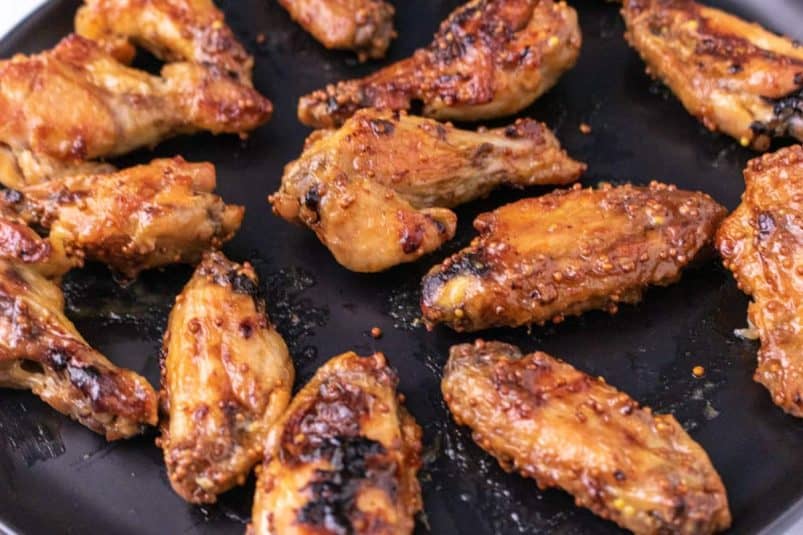 Sauced chicken wings on a black plate.
