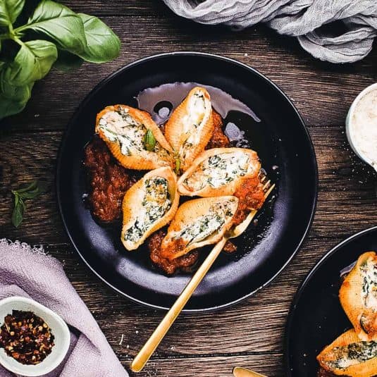 A serving basket of sweet potato fritters next to a bowl of dipping sauce and a single serving on a plate.