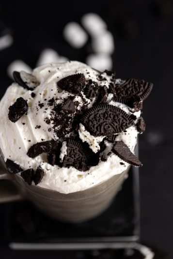Overhead view of oreo hot chocolate topped with whipped cream and lots of smashed oreo cookie pieces.