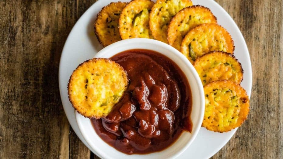Baked pickle cheese chips with bowl of ketchup on white plate.