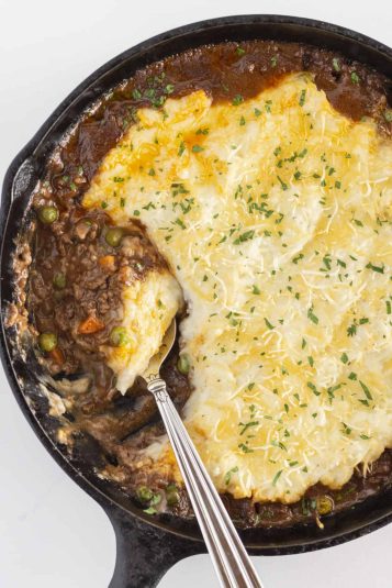 The finished shepherd's pie skillet in a cast iron skillet with a spoon.