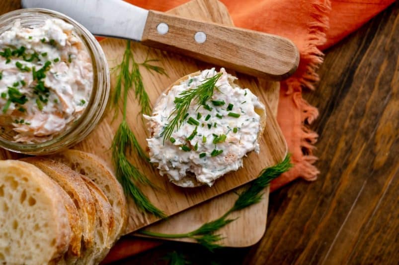 Smoked trout dip on baguette with wooden spreader.