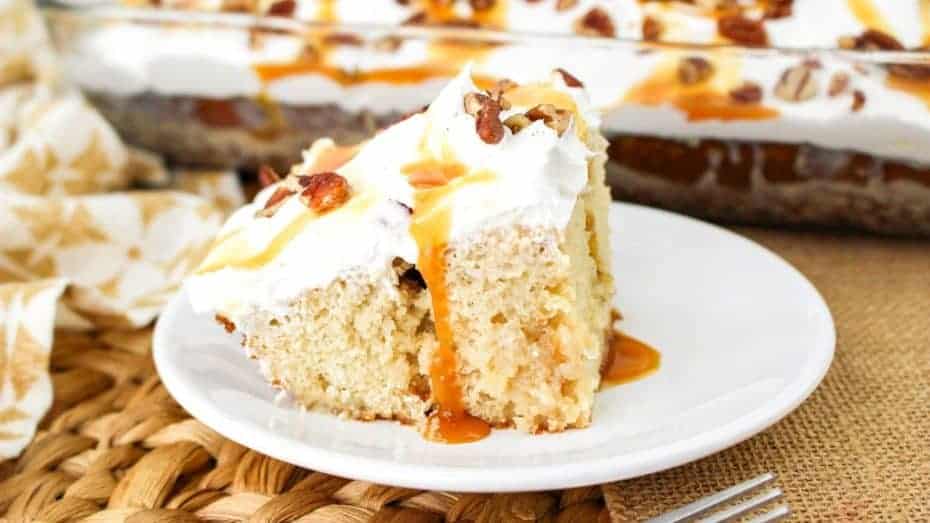 Bowl of creamy carrot soup garnished with small parsley pieces, placed on a patterned green and white napkin.