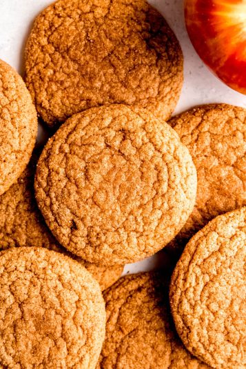 Closeup overhead shot of cinnamon sugar dusted chewy apple cider cookies in a pile on a plate.