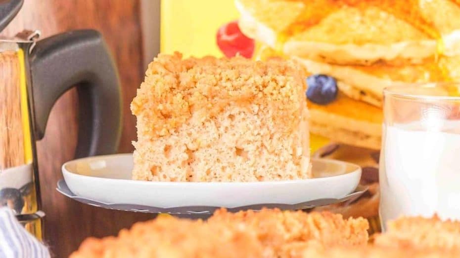 A bowl of rice topped with stir-fried beef and vegetables, with chopsticks. Green onions, a pot, and condiments are in the background.