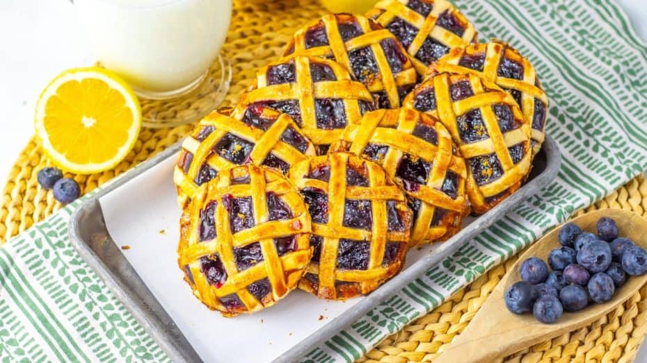 Three beef tacos with diced tomatoes, onions, and cilantro served in soft tortillas on a white plate with a green holder.
