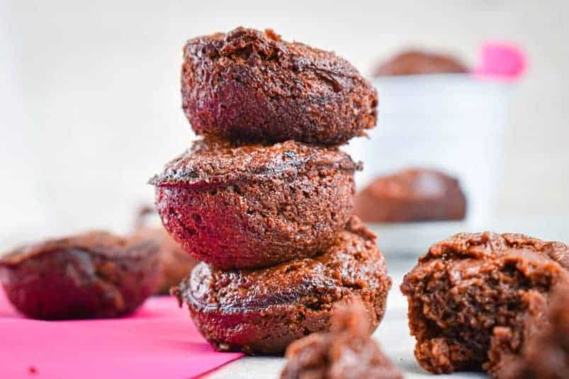 Brownie bites stacked on top of each other on pink napkin.