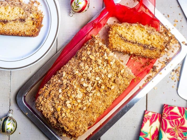 Coffee cake loaf with Christmas decorations on white wooden background.