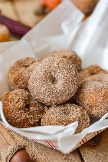 Cinnamon sugar coated pumpkin donuts in a white basket.