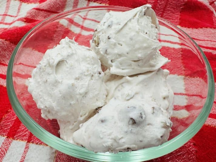 A plate of three pumpkin waffles topped with a pat of butter, syrup, and pecans.