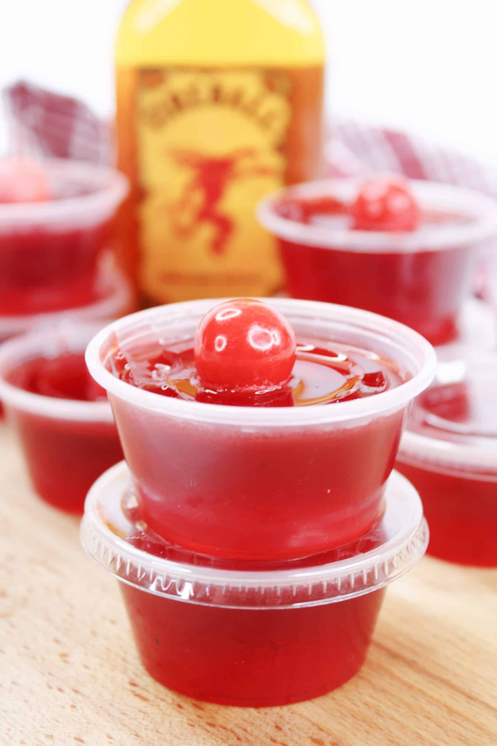two Fireball Jello shots with an Atomic Fireball on top sitting on top of each other in plastic cups. 